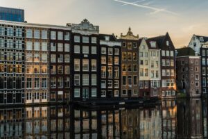 Foto van een rij grachtenhuizen aan een watergang met hun reflecties in het water. Met daarbij: Over BaoLiba – Revolutie in Influencer Marketing in Nederland